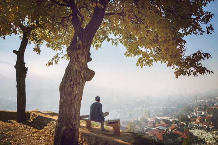 mężczyzna spogląda na miasto siedząc w parku